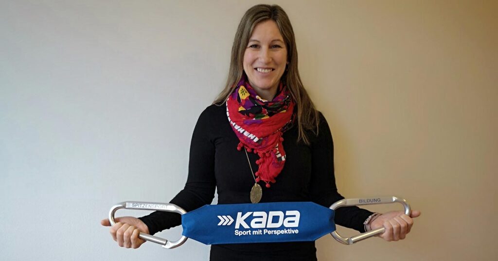 Ingrid Rumpfhuber posiert mit einem KADA Banner im Teambüro