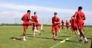 Aufwärmübung mit Trainingshütchen und Stangen für eine Gruppe vereinssuchender Fußballspieler