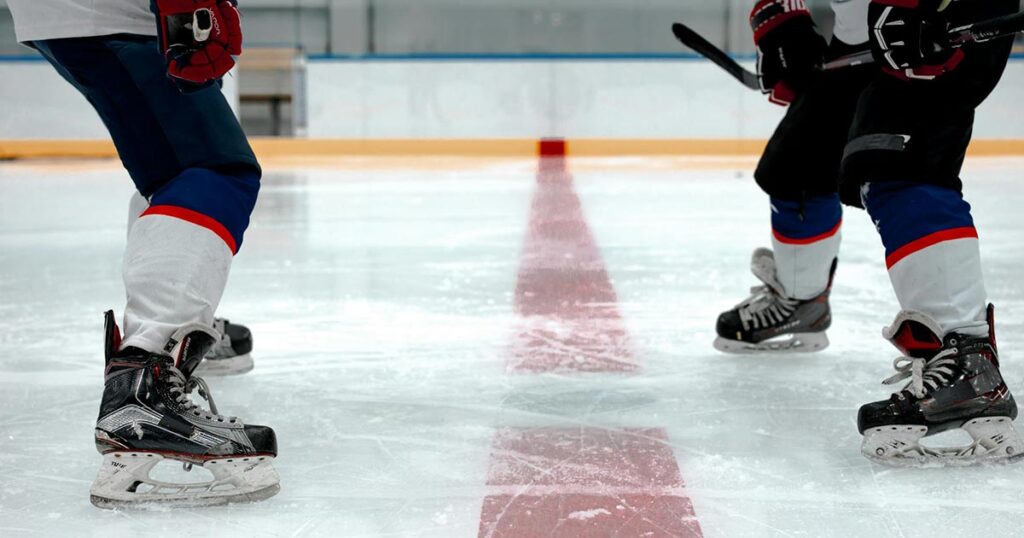 Zwei Eishockeyspieler stehen sich an der Mittellinie gegenüber