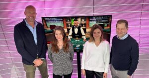 KADA Geschäftsführer Nik Berger mit Vertreter:innen von win2day vor einem Bildschirm, das eine Spielszene aus dem Onlinecasino zeigt
