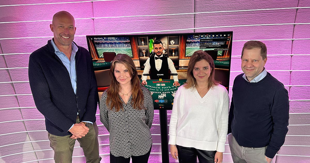 KADA Geschäftsführer Nik Berger mit Vertreter:innen von win2day vor einem Bildschirm, das eine Spielszene aus dem Onlinecasino zeigt
