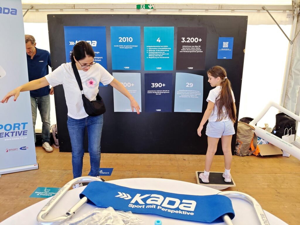 Zwei Besucherinnen probieren bei KADAs Mitmachstation am Tag des Sports, ihr Gleichgewicht auf Balance-Boards zu halten