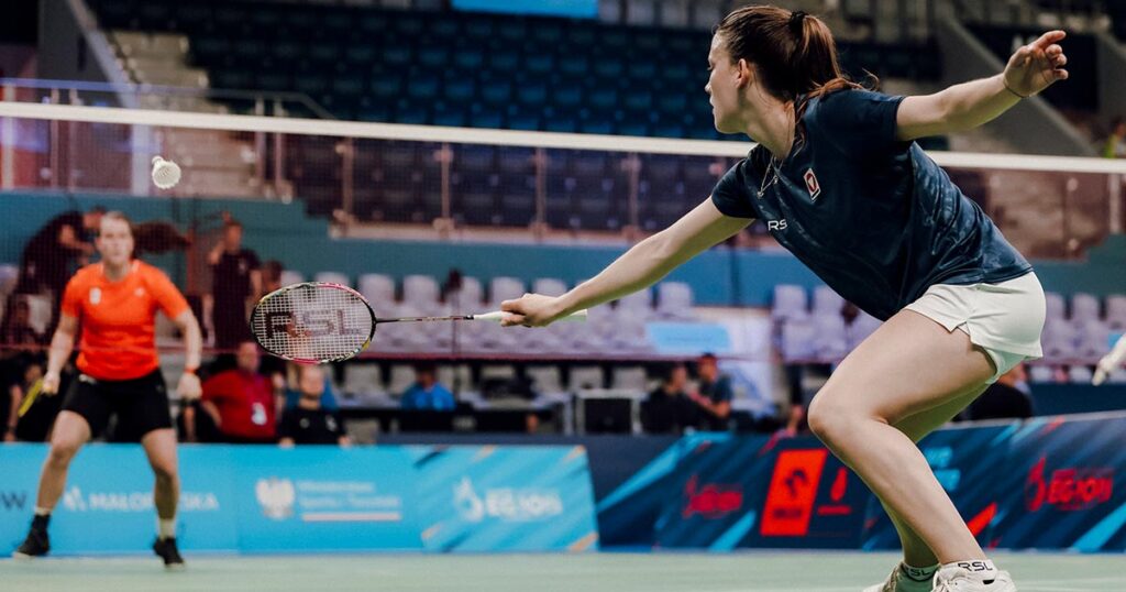 Matchszene: Katharina streckt sich, um einen tiefen Ball über das Netz zurückzuschlagen